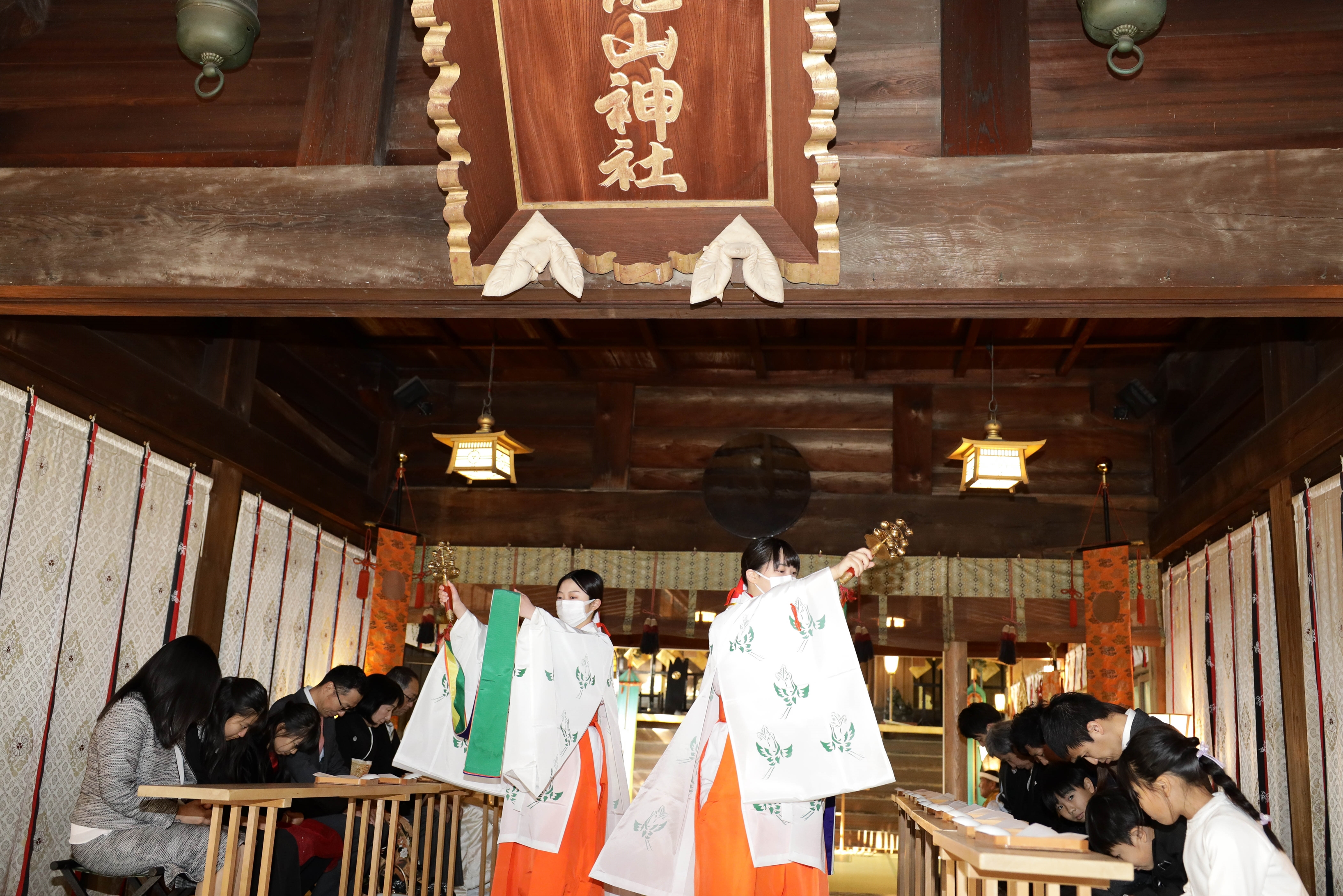 二荒山神社の拝殿で神楽鈴を振って祈りを捧げる巫女と参列者
