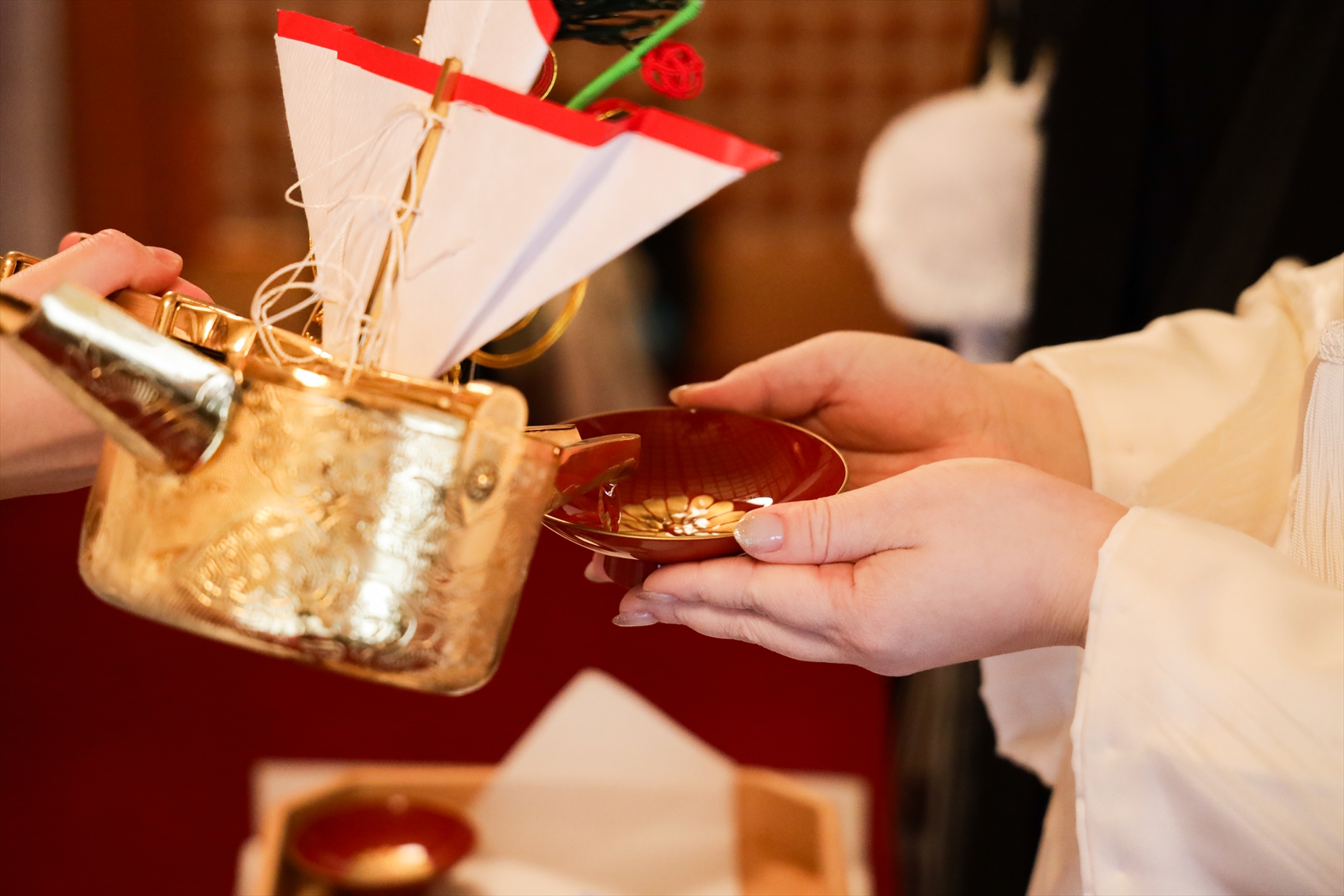 三々九度の盃にお神酒が注がれる白無垢姿の新婦の手元