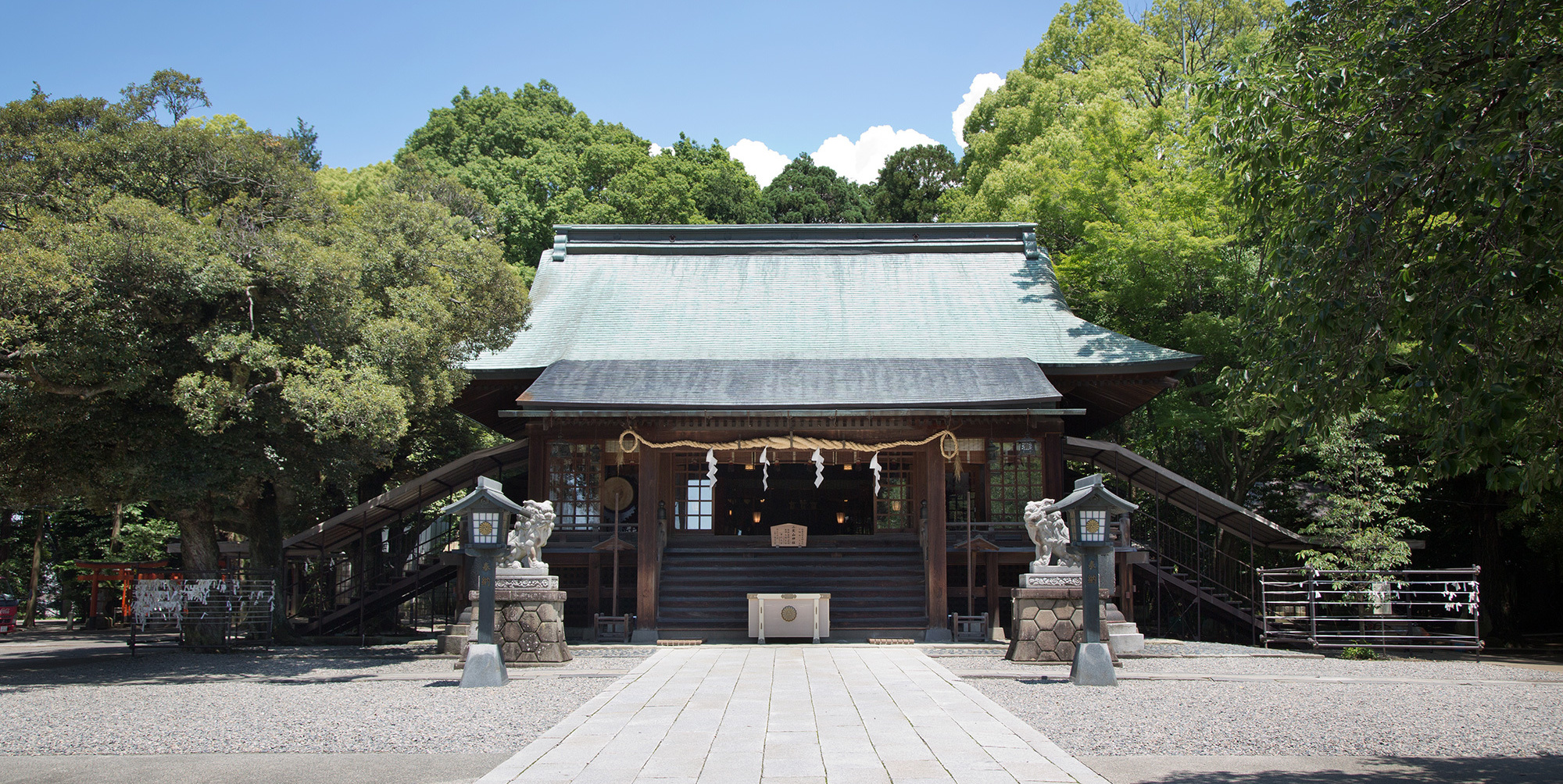 青空の下に構える二荒山神社拝殿の正面と参道に並ぶ狛犬と石灯籠