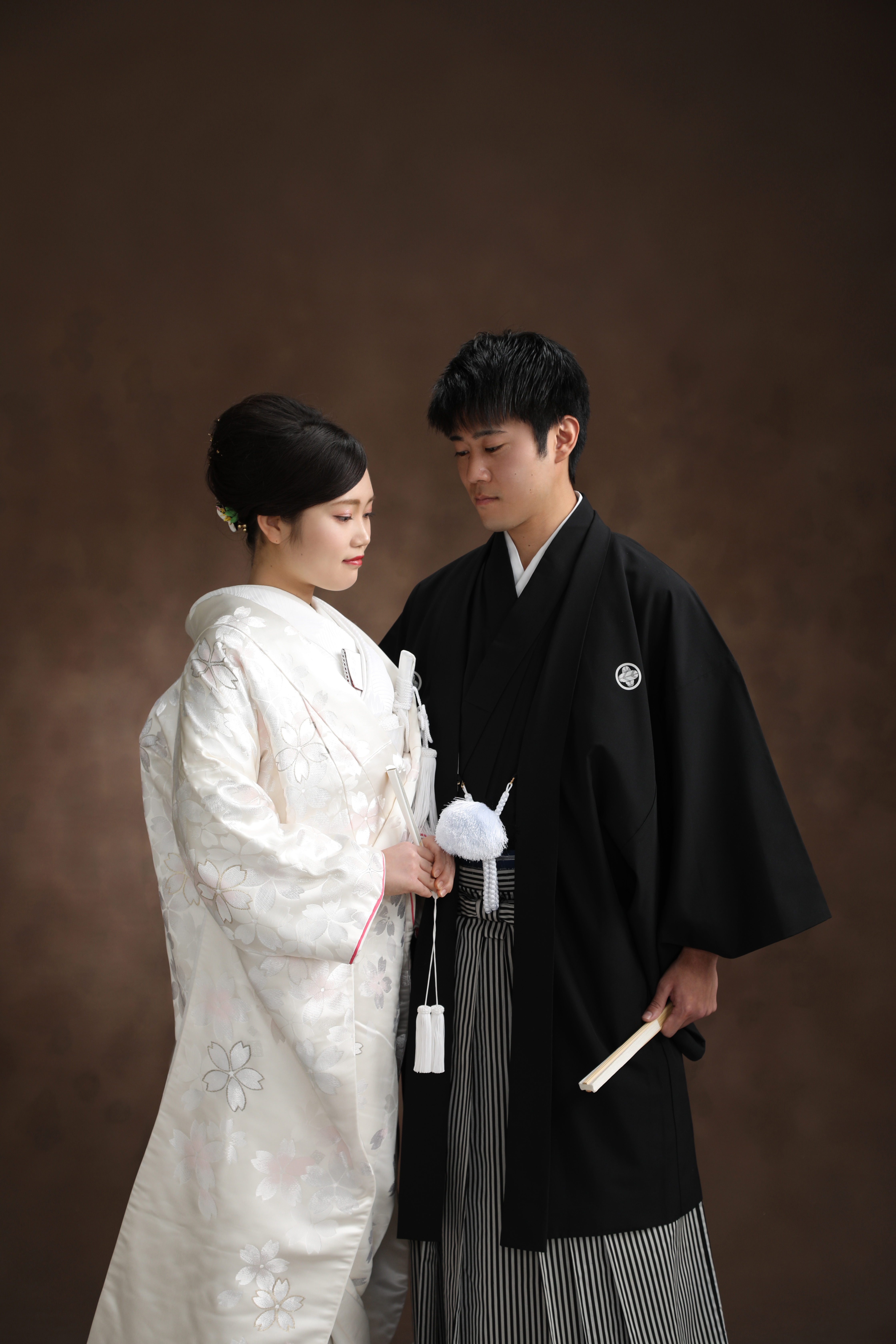 桜柄の白無垢の新婦と黒紋付袴の新郎が寄り添い目を伏せる