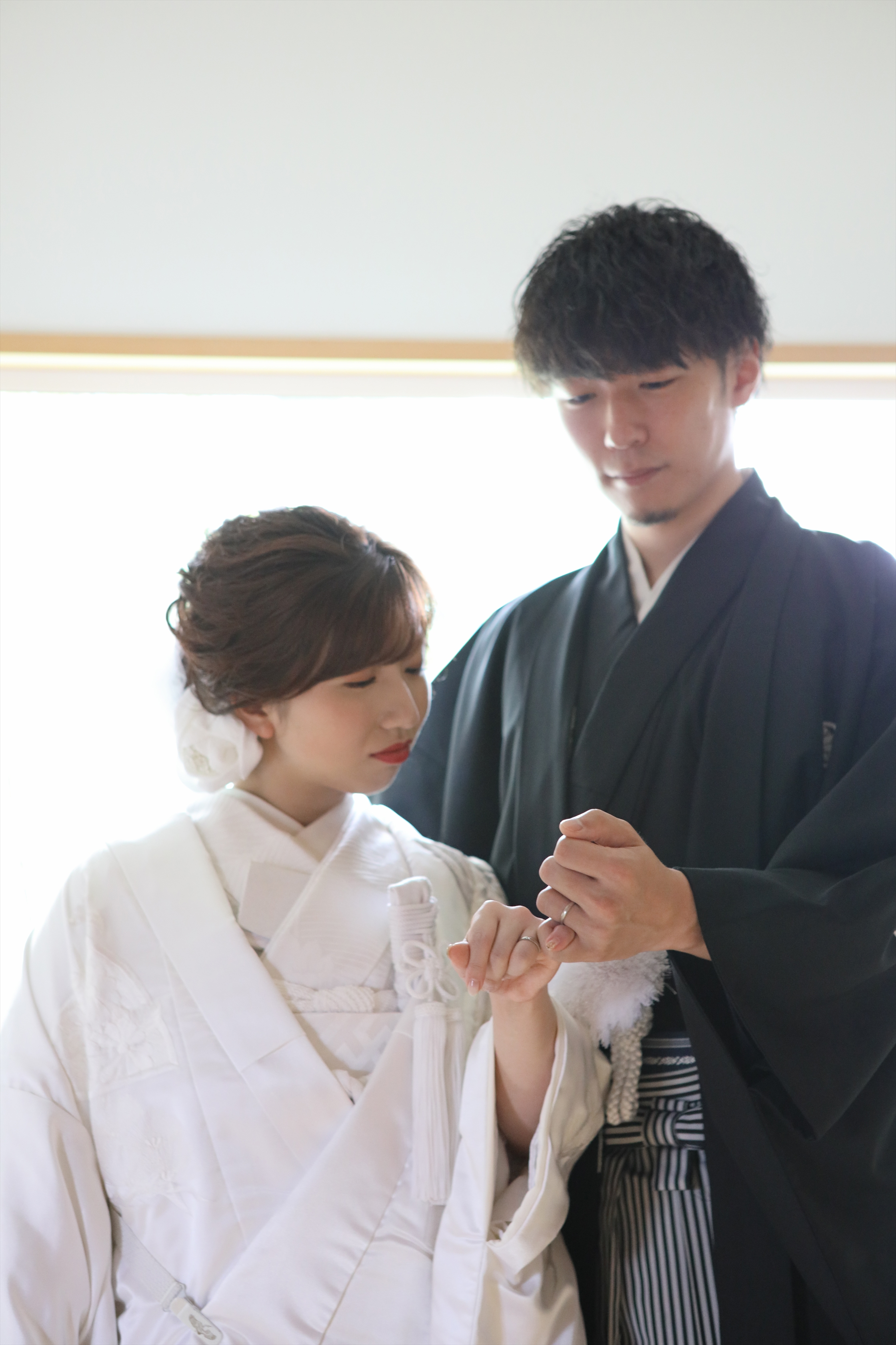 白無垢の新婦の指に結婚指輪をはめる黒紋付袴の新郎