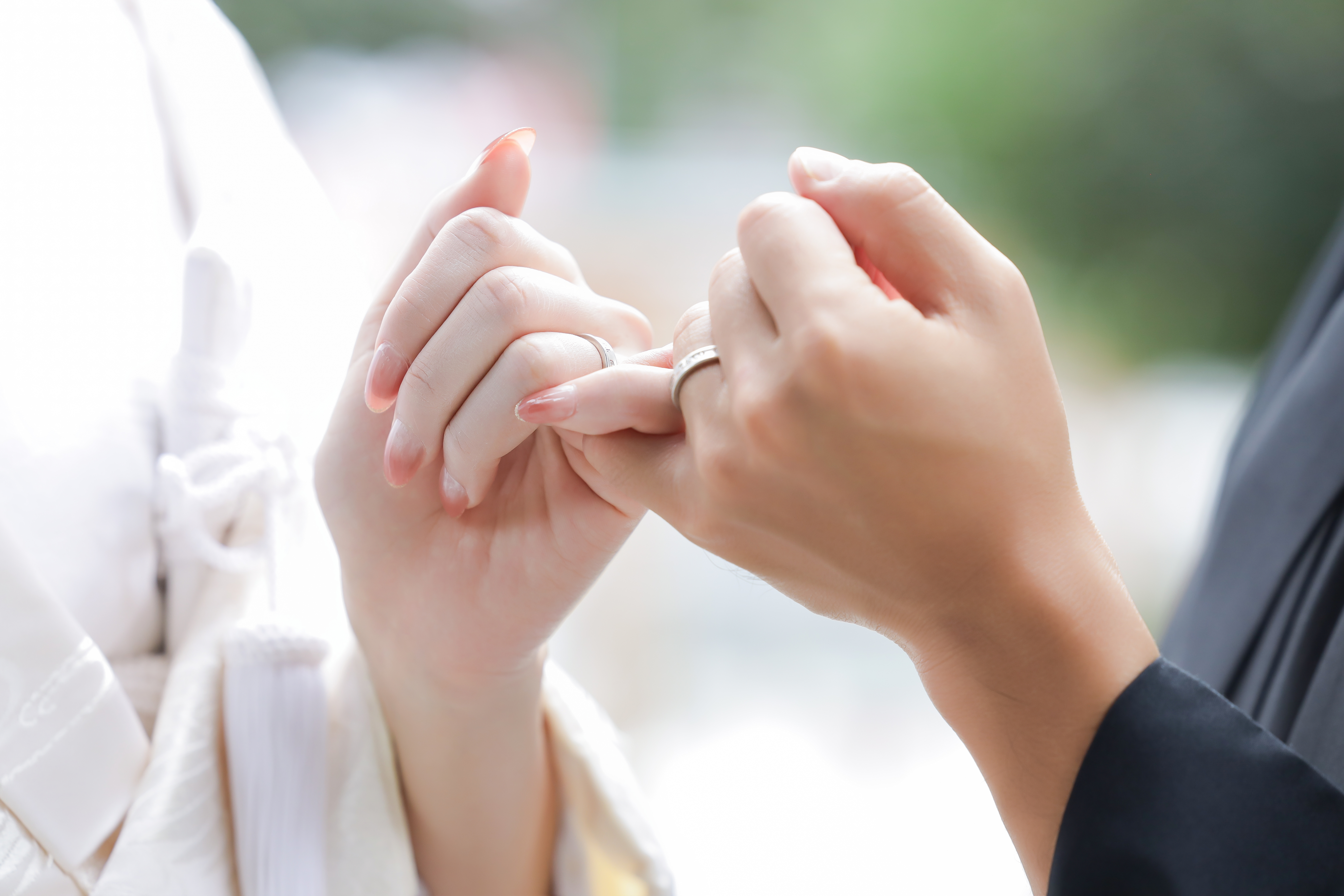 白無垢と黒紋付の袖から伸びた結婚指輪をつけた指切りの手元