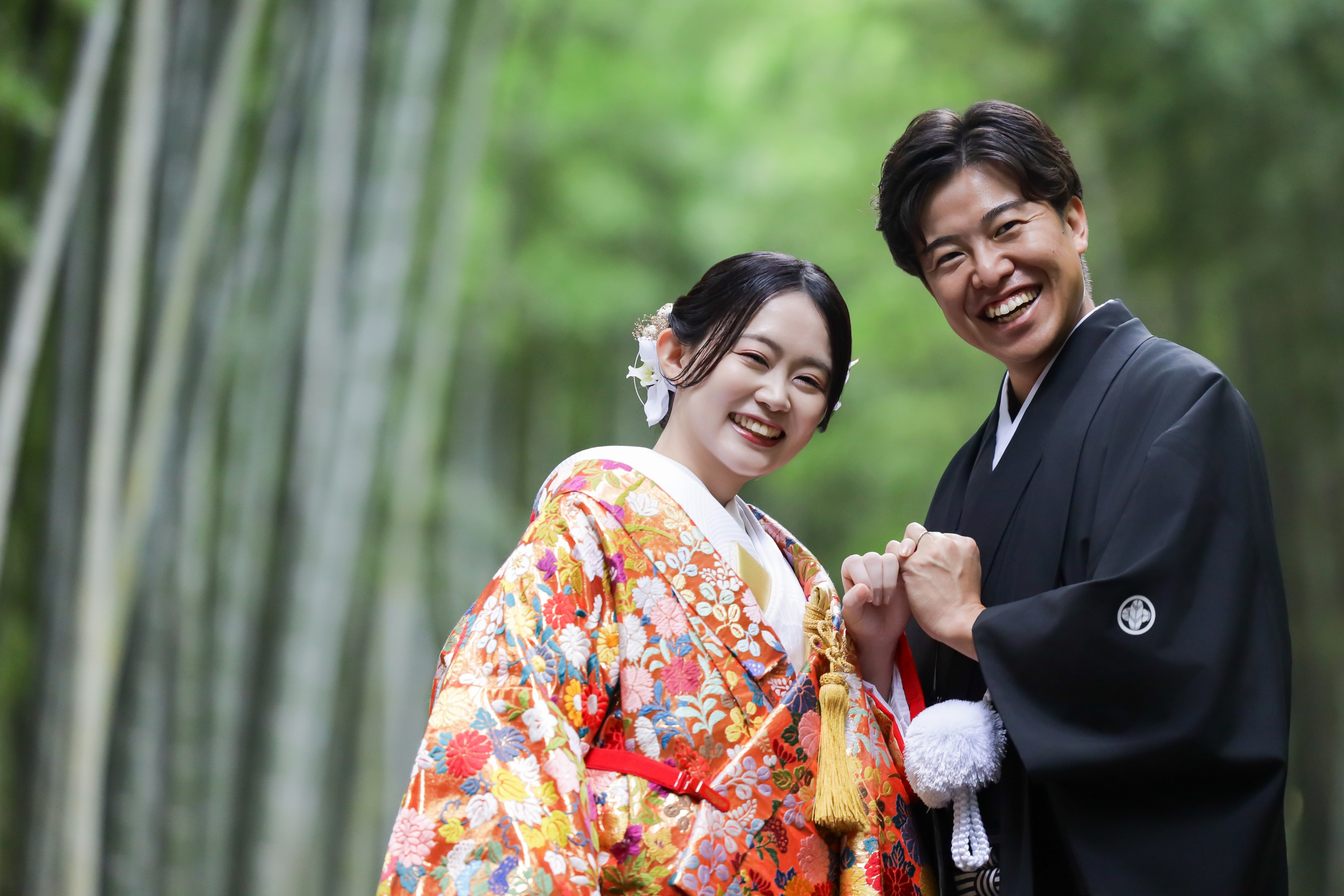 竹林で指切りをして笑い合う色打掛の新婦と黒紋付袴の新郎