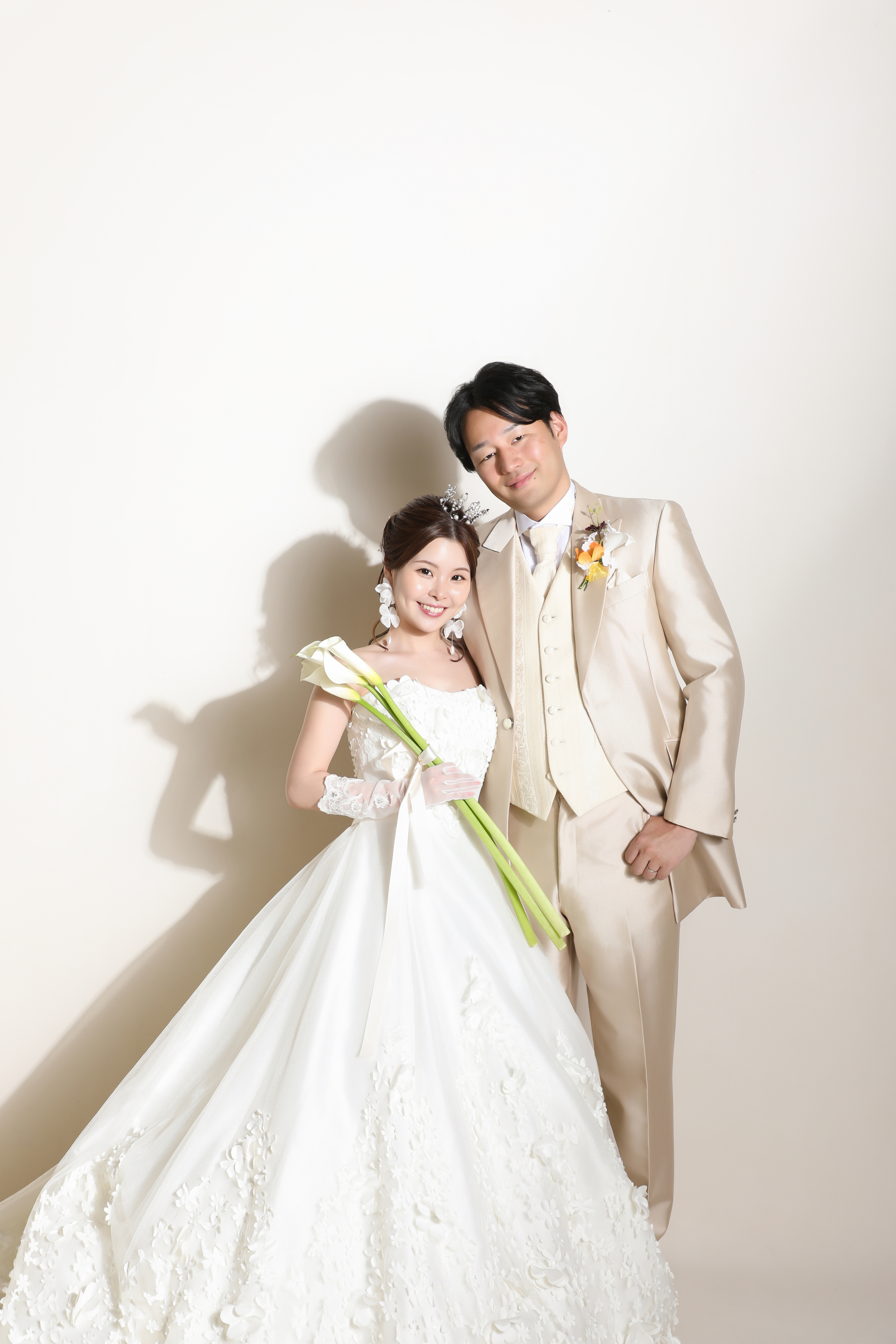 カラーのブーケを抱えたウェディングドレスの新婦とシャンパンゴールドのタキシードの新郎