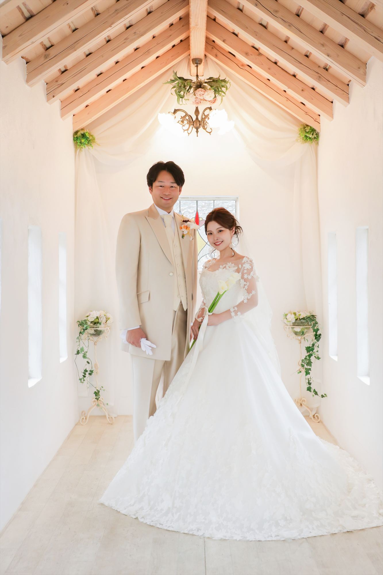 白いチャペルでウェディングドレスとタキシード姿で寄り添う新郎新婦