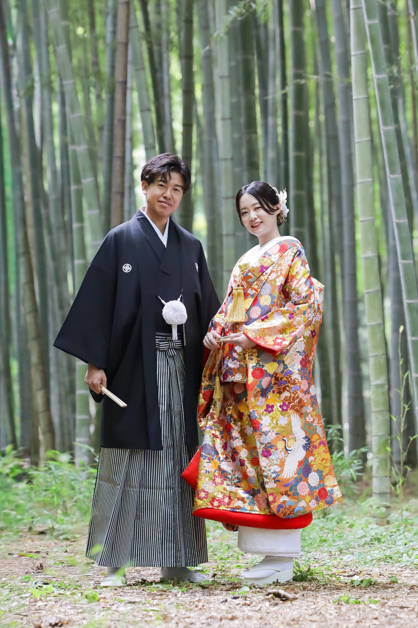 竹林で色打掛と紋付袴姿で並ぶ新郎新婦の和装ロケーション撮影