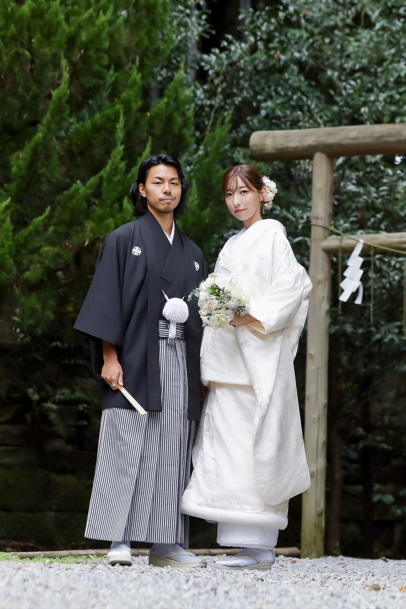 鳥居の前で白無垢と紋付袴姿で並ぶ新郎新婦の和装フォトウェディング