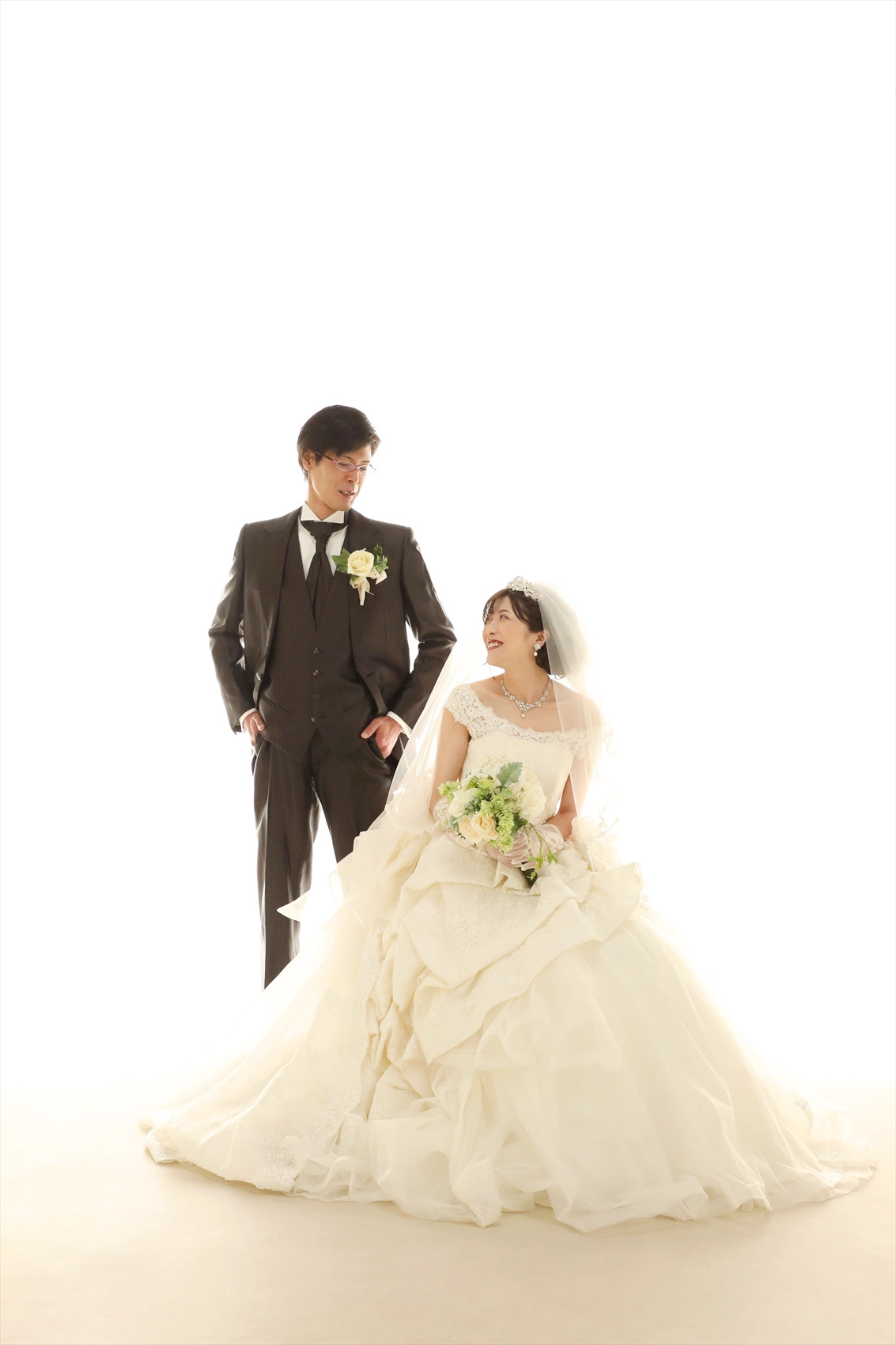 白ホリゾントで寄り添うウェディングドレスの新婦とタキシードの新郎