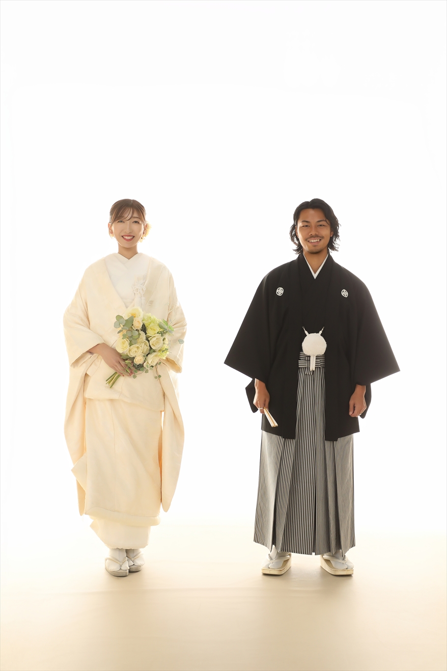 白ホリゾントに並んで立つ白無垢姿の新婦と黒紋付袴の新郎
