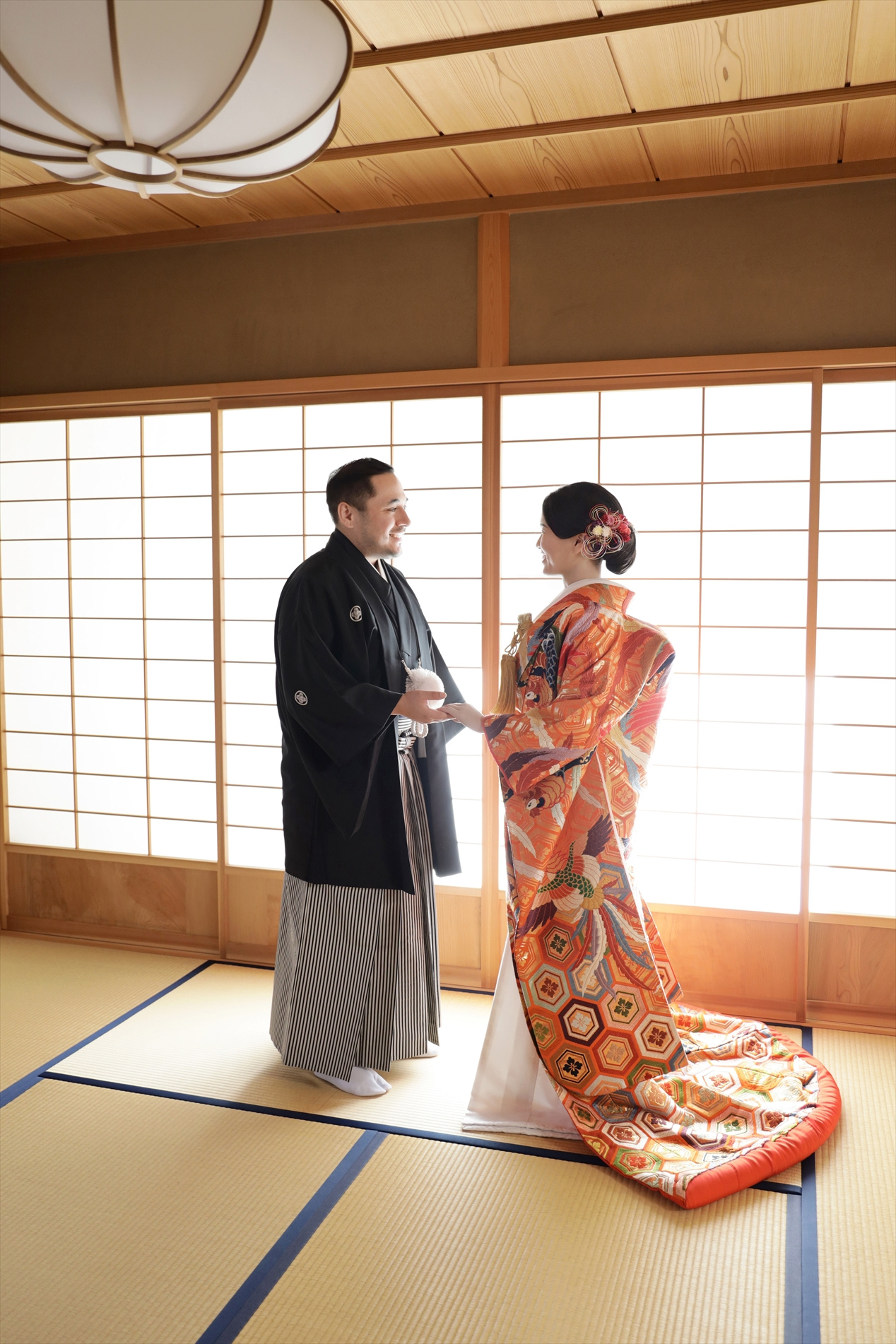障子の光が差す和室で向かい合う色打掛の新婦と黒紋付袴の新郎